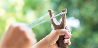 Hand shooting a slingshot during outdoor target practice using equipment from GX Slingshots online store